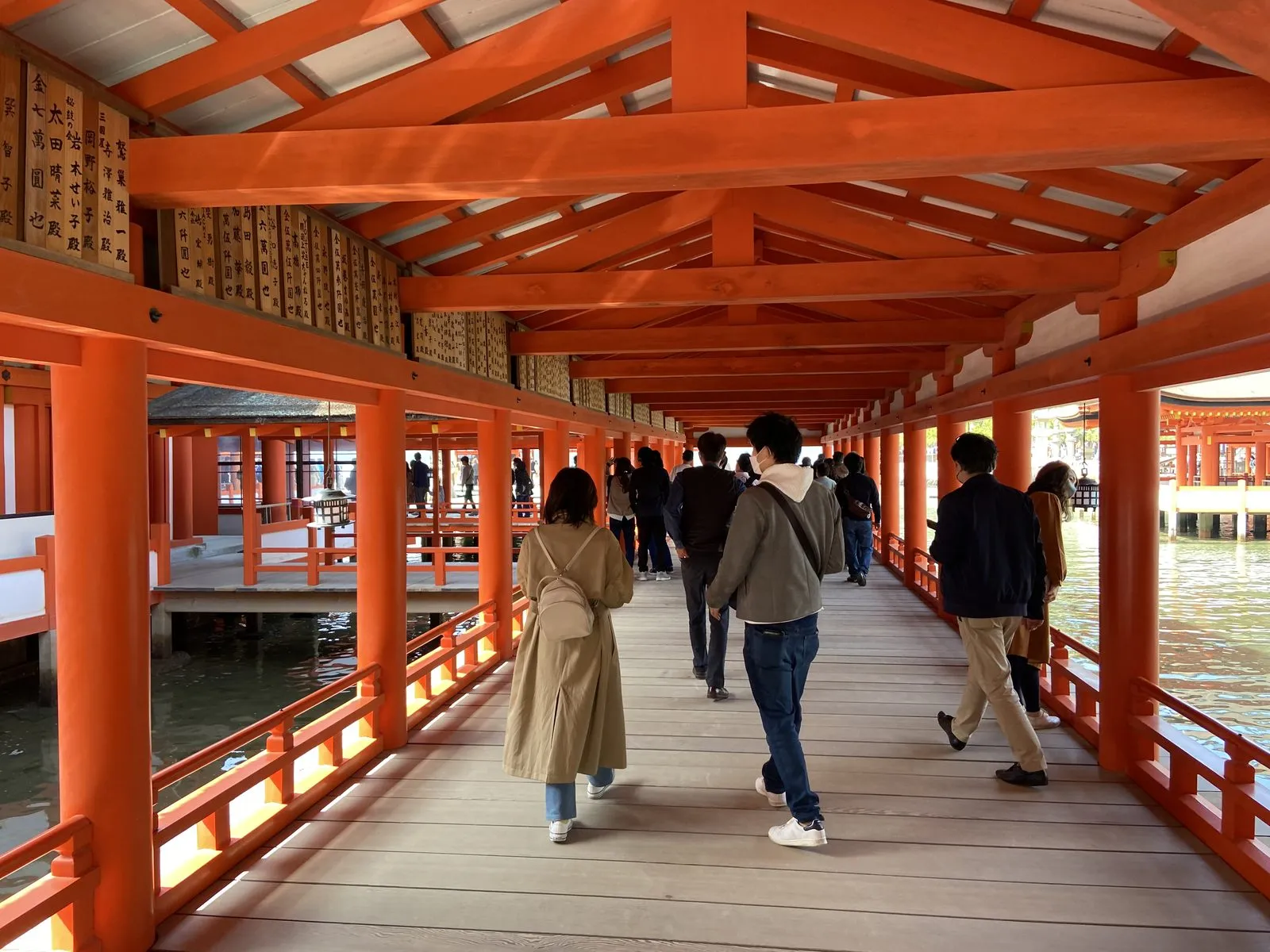 Inside Itsukushima Shrine's corridors over the water, vermilion columns and wooden boardwalk