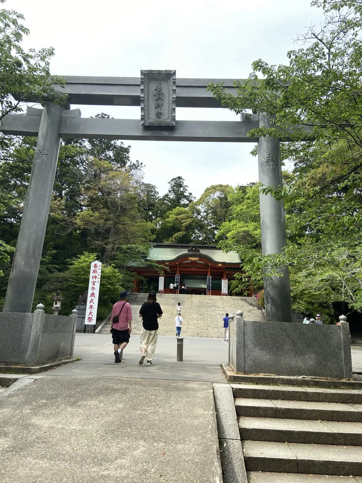 The grey torii gate of Katori Jingu with the tree-lined approach beyond