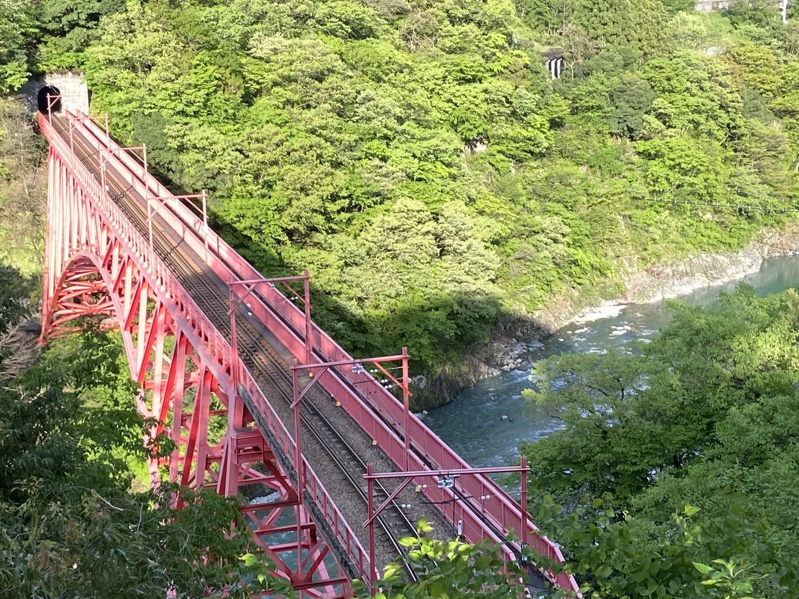 The red Shin-Yamabiko railway bridge across the Kurobe river seen from the Yamabiko viewpoint