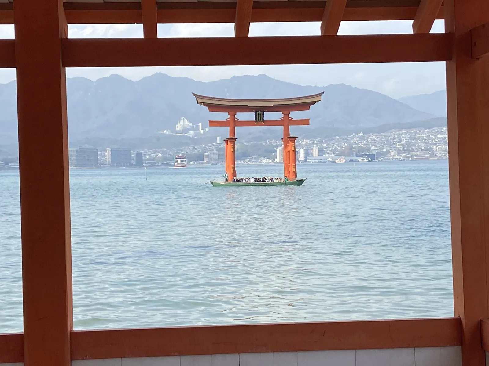 The great torii of Itsukushima Shrine framed by the shrine corridors, a tour rowboat passing beneath it
