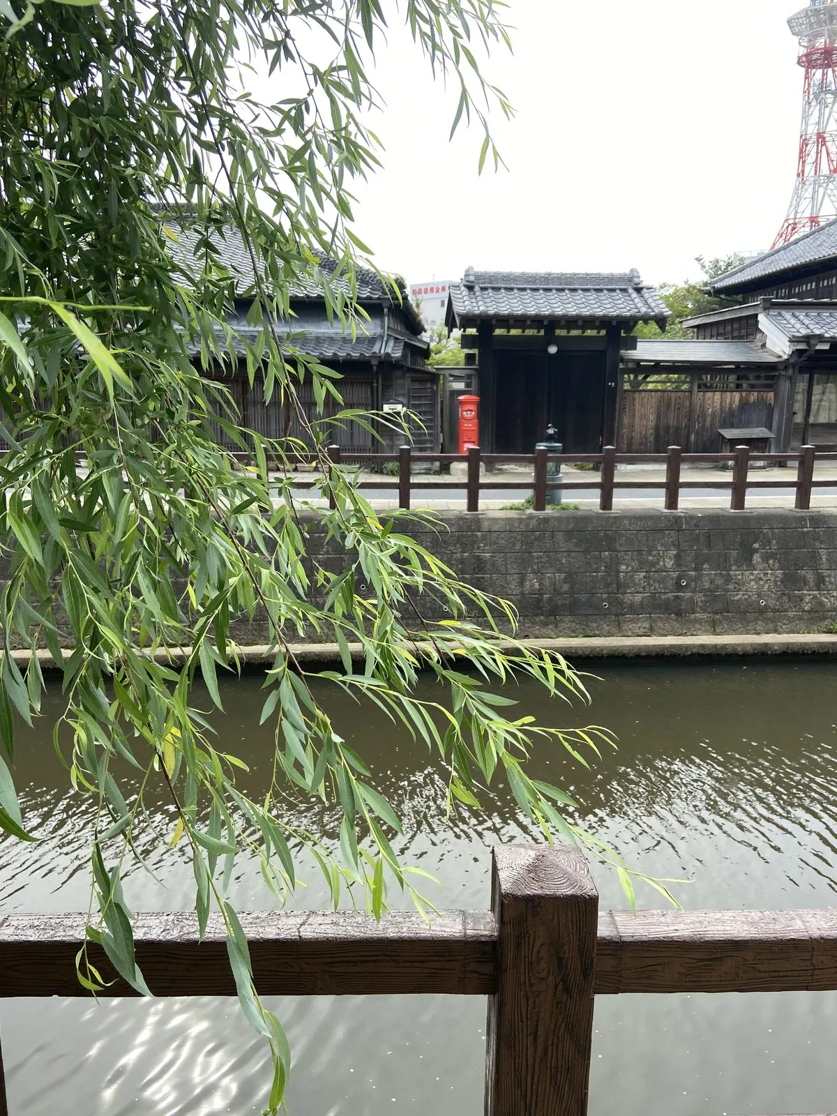 Willow branches over the Sawara canal with a red cylindrical postbox across the water