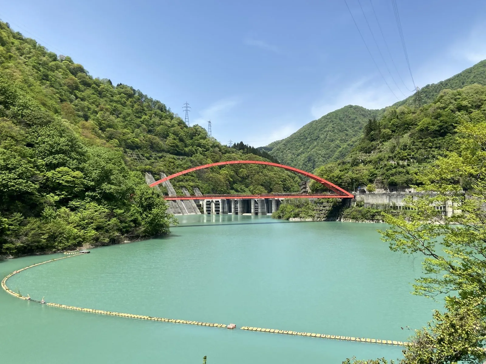 A red arch bridge spanning the emerald reservoir